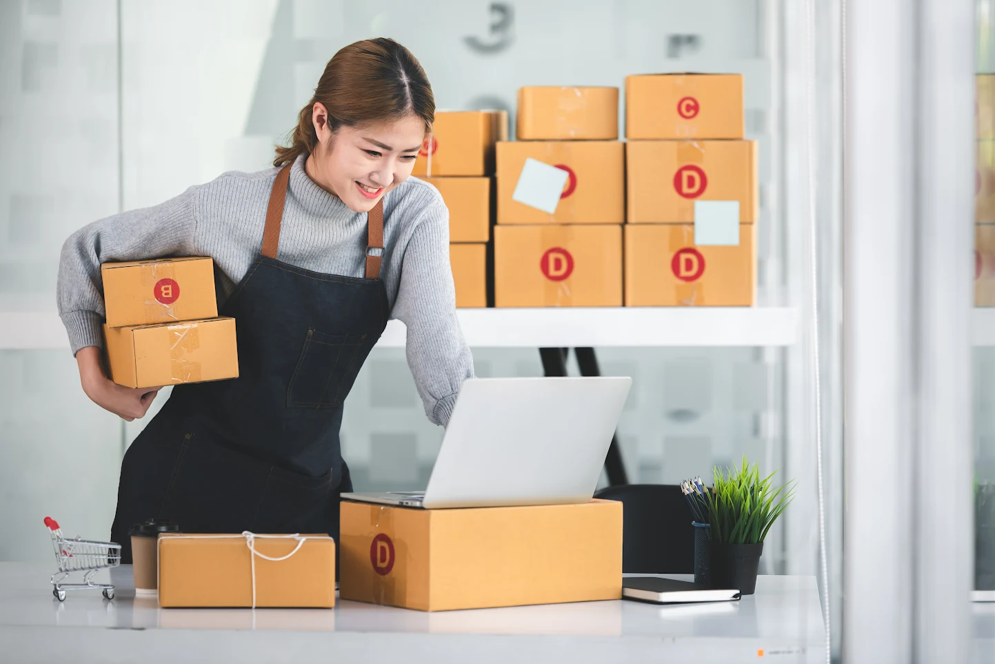 Woman packing parcels and checking an order on a laptop
