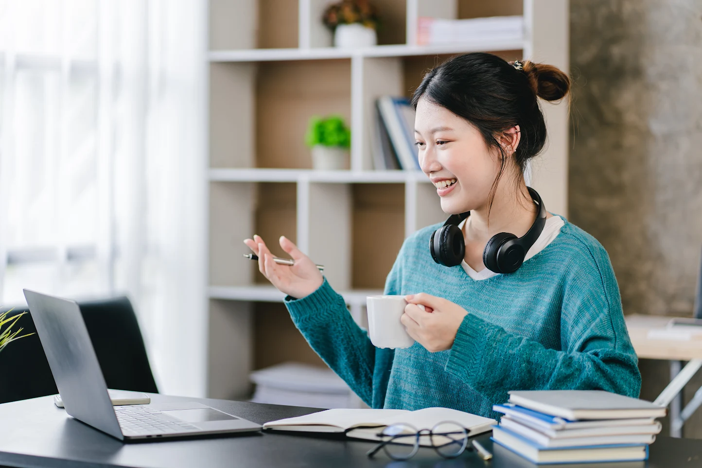 Woman on a video call at her desk with a laptop and headphones